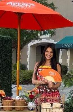 Female brand ambassador under an umbrella with flowers representing Aperol Spritz.